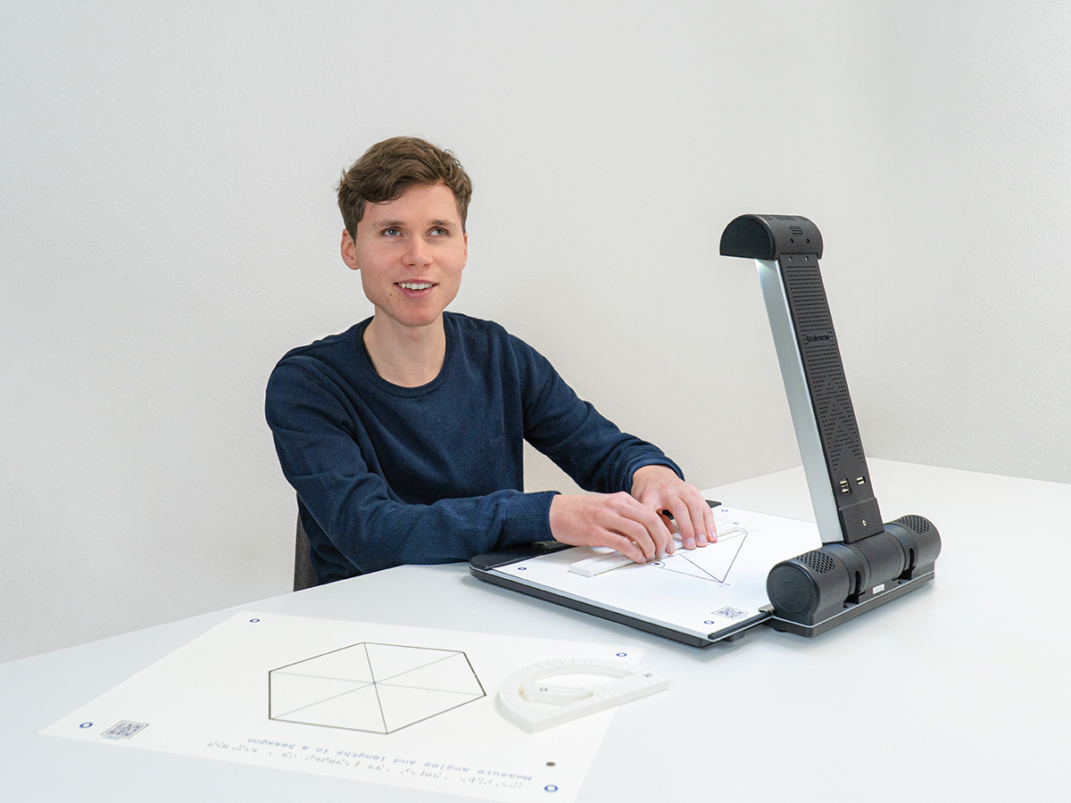 Billede af en person som sidder med Tactonom Reader Flex foran sig, i gang med at bruge Matematiksæt