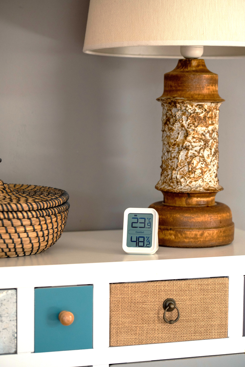 BIllede af IKONN Stuetermometer placeret på kommode ved siden af lampe