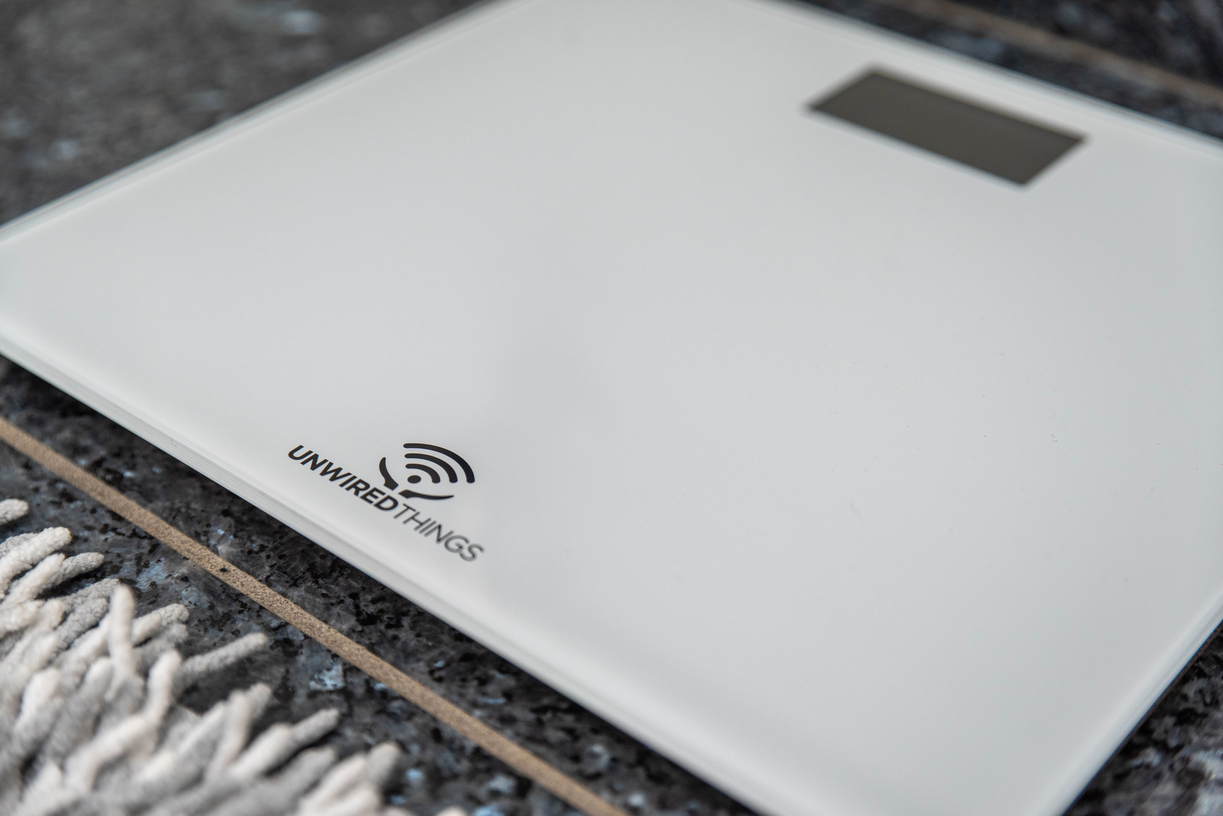 Billede af IKONN Badevægt placeret på gulv ved siden af et gulvtæppe