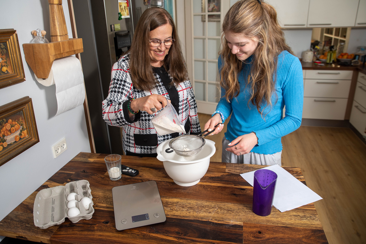 Billede af IKONN Køkkenvægt på et køkkenbord med to personer som er i gang med at sigte mel