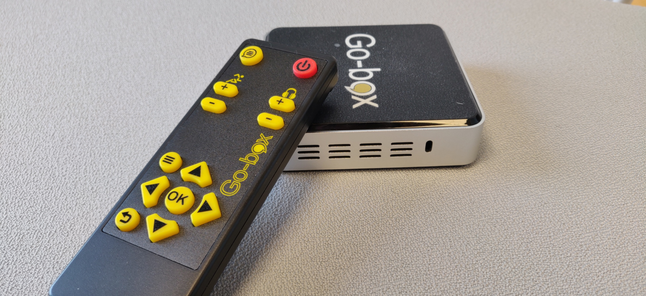 Billede af fjernbetjening til Go-box placeret oven på en Go-box enhed